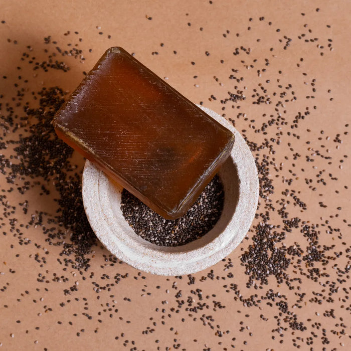 Handmade coffee and cocoa exfoliating soap bar displayed on a bowl with natural exfoliating ingredients.